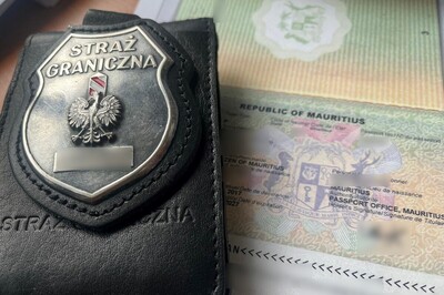 Na otwartym paszporcie obywatela Mauritiusu leży odznaka SG.