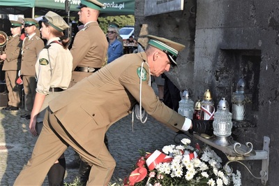 Przedstawiciel kaosg składa znicz pod pomnikiem upamiętniającym ofiary drugiej wojny światowej w węgierskiej górce