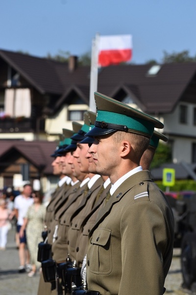 funkcjonariusze kompanii reprezentacyjnej sg stoją na baczność w szpalerze. w tle powiewają biało czerwone flagi