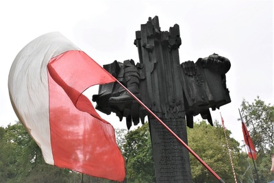 na zdjęciu widoczny jest Pomnik żołnierzy września i armii karków. przed pomnikiem powiewa białoczerwona flaga Polski