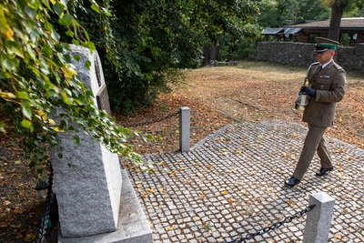 funkcjonariusz straży granicznej składa pod pomnikiem patriotycznym znicz pamięci.