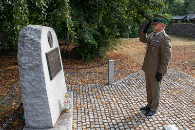 funkcjonariusz straży granicznej oddaje honor przed pomnikiem poświęconym poległym, żołnierzom podczas drugiej wojny światowej.