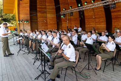 muzycy orkiestry reprezentacyjnej straży granicznej grający podczas koncertu w amfiteatrze. funkcjonariusze ubrani są w białe służbowe koszule z pagonami oraz spodnie koloru khaki. dyryguje nimi ich naczelnik