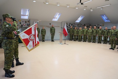 na pierwszym planie widoczny sztandar karpackiego oddziału straży granicznej. Na drugim planie stoją z prawej strony naczelnicy wydziałów a na środku stoi komendant Karpackiego oddziału straży granicznej wraz ze swoimi zastępcami. Między nimi widoczna jest białoczerwona flaga.