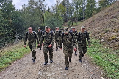 funkcjonariusze straży granicznej idący marszem w terenie górzystym podczas odprawy kadry kierowniczej. w tle widoczne góry oraz ogólnie krajobraz górzysty.