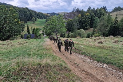 funkcjonariusze straży granicznej idący marszem w terenie górzystym podczas odprawy kadry kierowniczej. w tle widoczne góry oraz ogólnie krajobraz górzysty.