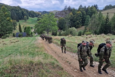 funkcjonariusze straży granicznej idący marszem w terenie górzystym podczas odprawy kadry kierowniczej. w tle widoczne góry oraz ogólnie krajobraz górzysty.