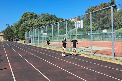 funkcjonariusze zaliczają Test Coopera. biegają na bieżni sportowej. na sobie mają strój do wykonywania ćwiczeń.