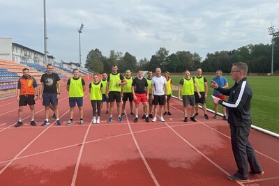 funkcjonariusze straży granicznej stoją w szeregu. funkcjonariusz prowadzący zajęcia omawia zasady. wszyscy ubrani sa w strój do wykonywania ćwiczeń. całość odbywa się na bieżni sportowej.