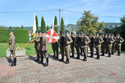 kompania reprezentacyjna straży granicznej złożona z funkcjonariuszy straży granicznej maszeruje. idą czwórkami. przed kompania maszeruje dowódca kompanii a za nim poczet sztandarowy ze sztandarem.