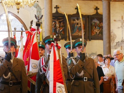 widoczny jest sztandar wraz z pocztem sztandarowym złożonym z funkcjonariuszy straży granicznej. prezentują sztandar w kościele.