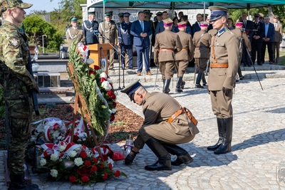 funkcjonariusze straży granicznej, którzy maja na sobie mundury nawiązujące do żołnierzy korpusu ochrony pogranicza składają znicz pod pomnikiem.