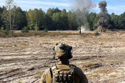 funkcjonariusze straży granicznej z Karpackiego Oddziału straży granicznej wykonujący ćwiczenia na poligonie. ćwiczenie polega na rozminowaniu min. na zdjęciu ukazany jest wybuch i ziemia razem z kurzem unosi się po wybuchu miny. obserwuje to funkcjonariusz straży granicznej.