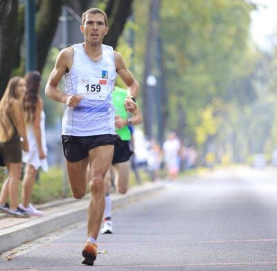 funkcjonariusz straży granicznej biegnący ulicami miasta podczas zawodów sportowych. ubrany jest w strój sportowy .