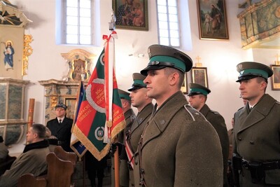 wnętrze kościoła w tropiu. na pierwszym planie sztandar kaosg i poczet sztandarowy. w tle uczestnicy eucharystii. widać boczny ołtarz, a na ścianach obrazy