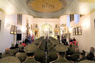 ujęcie wnętrza kościoła w tropiu - widok od tylnych drzwi. uczestnicy mszy świętej siedzą, cztery poczty sztandarowe stoją po lewej i prawej stronie pod ścianą. Na pierwszym planie funkcjonariusze kompanii reprezentacyjnej stojący w równiuteńkim  dwuszeregu - widok z tyłu