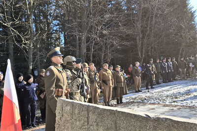 na zdjęciu widoczni są uczestniczy uroczystości. głównie osoby umundurowane z różnych formacji. m. in. wojska, policji i straży granicznej.  na pierwszym planie widoczny funkcjonariusz straży granicznej ubrany w mundur historyczny korpusu ochrony pogranicza.