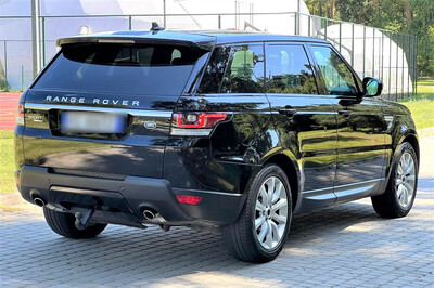 Parking na zewnątrz . Jeden z odzyskanych luksusowych samochodów marki  Land Rover, kolor czarny - widok z tyłu.