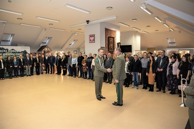 Sala odpraw prowadzący uroczystość melduje pracowników do uroczystej zbiórki. W tle stoją pracownicy kaosg - kilkadziesiąt osób