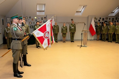 Sala odpraw. na pierwszym planie poczet sztandarowy kaosg, dalej komendant kaosg i jego zastępcy oraz kadra kierownicza oddziału