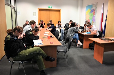 pOMIESZCZENIA psG W kRAKOWIE - bALICACH. funkcjonaRIUSZE Uczestniczący w szkoleniu siedzą przy biurkach. zapoznają się z dokumentami. korzystają z lupy powiększającej.