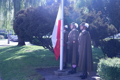 poczet flagowy funkcjonariuszy straży granicznej wciąga na maszt flagę polski