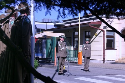 funkcjonariusz straży granicznej przemawia przez mikrofon podczas uroczystej zbiórki