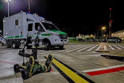 Godziny nocne. Na płycie lotniska  pojazd specjalistyczny pirotechniczny Straży Granicznej. Na pierwszym planie robot pirotechniczny.