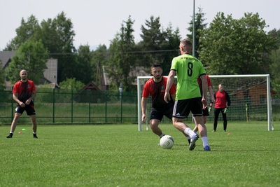 zawodnicy grający w piłkę nożna w żółtych i czerwonych strojach, piłkarz grający w żółtym stroju prowadzi piłkę w stronę zawodnika grającego w czerwonym stroju