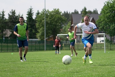 piłkarz grający białym stroju biegnie w stronę piłki