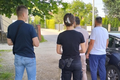 nieumundurowani funkcjonariusze  kontroluj ą dwóch cudzoziemców, stojących przy samochodzie