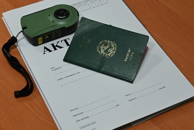 na zdjęciu widać teczkę akt sprawy cudzoziemca, na niej jest umieszczony paszport obywatela nepalu oraz urządzenie do weryfikacji paszportów