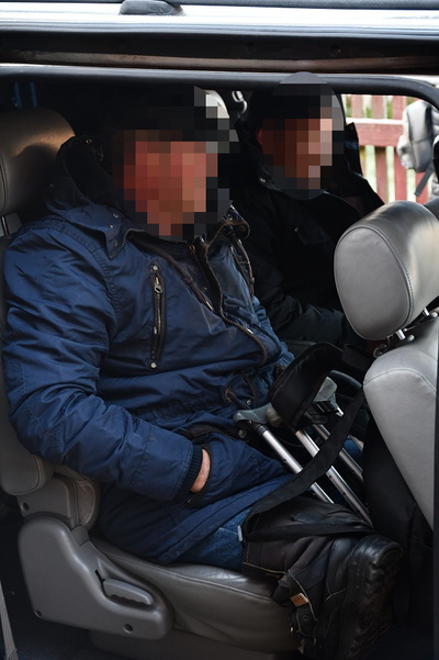 Zdjęcie siedzącego w pojeździe służbowym na tylnym siedzeniu  niepełnosprawnego, który trzyma kulę w ręce.