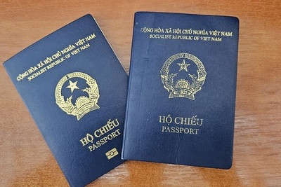 Na zdjęciu widać dwa granatowe paszporty ze złotymi napisami i logiem widocznym na środku. Paszporty widać na brązowym tle.