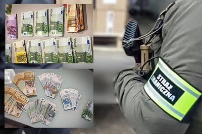 Na zdjęciu widać po lewej stronie plik banknotów ułożonych na stole. Po prawej stronie na zdjęciu widać fragment mężczyzny w zielonej bluzie z bronią w ręku. Na przedramieniu widoczna jest opaska z napisem Straż Graniczna.