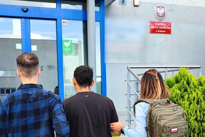 Na zdjęciu widać trzy osoby stojące przed budynkiem.