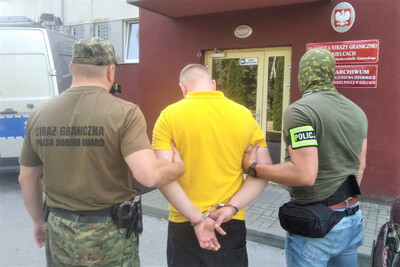Zatrzymany obywatel ukrainy prowadzony jest przez jednego strażnika granicznego i jednego policjanta do siedziby placówki straży granicznej w kielcach