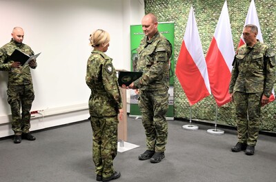 generał gratuluje nowo powołanej funkcjonariuszce. w tle białoczerwone flagi i uczestnicy uroczystości