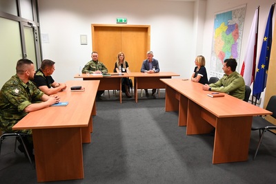 uczestnicy spotkania - 9 osób siedzą przy stołach ułożonych w kształcie litery U, prowadzą rozmowę.
