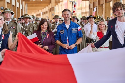 Delegacja z astronautą i polską flagą w pierwszym planie podczas obchodów Dnia Narodowego Polski na Expo.