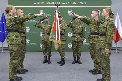 4 funkcjonariuszy sg, w tym dwie kobiety - na inauguracji roku akademickiego ślubują na sztandar wssg. sztandar trzyma funkcjonariusz obok niego stoją dwaj funkcjonariusze