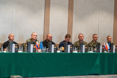 Uczestnicy szkolenia siedzą przy stole prezydialnym. Na stole flagi słowacji, polski i unijna.