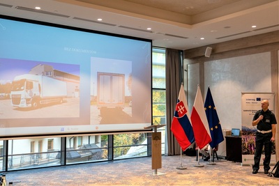 Wystąpienie prelegenta. Na monitorze wyświetla się prezentacja