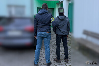 Zatrzymany cudzoziemiec jest wprowadzany przez funkcjonariusza straży granicznej do budynku