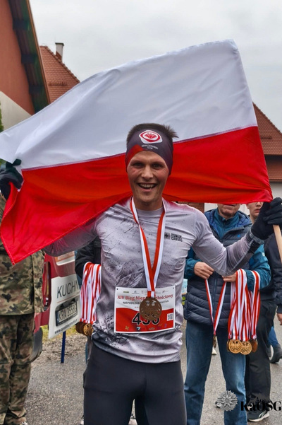 Na zdjęciu widać mężczyznę w stroju sportowym który trzyma flagę biało-czerwoną