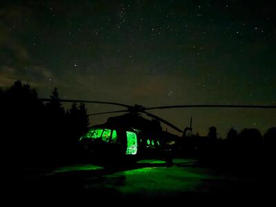 Noc. Widać lekko podświetlony zielonym światłem śmigłowiec.