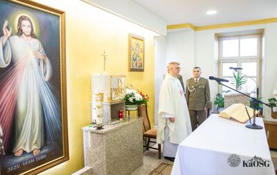 wnętrze kaplicy miłosierdzia bożego w siedzibie kaosg. przy ołtarzu ksiądz w ornacie, w tle dwóch funkcjonariuszy - ceremoniałów. Widać obraz miłosierdzia bożego oraz matki boskiej