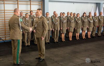 hala sportowa, funkcjonariusz składa meldunek genarałowi -  w tle kadra kierownicza oddziału stojąca w dwuszeregu