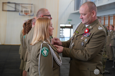 hala sportowa. generał przypina medal odznaczonym funkcjonariuszom.