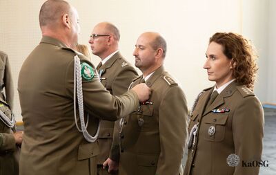 hala sportowa. generał przypina medal odznaczonym funkcjonariuszom.